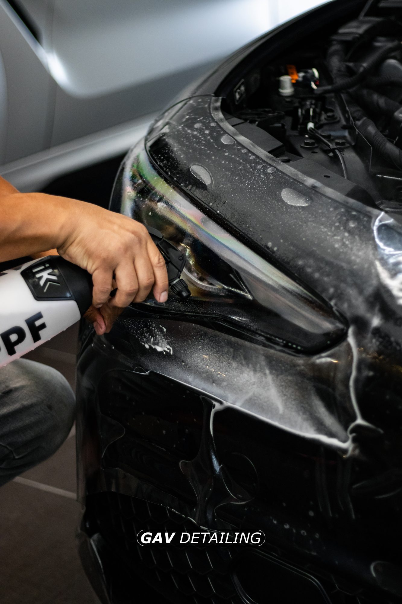 Técnico de GAV Detailing instalando film de protección de pintura PPF en la defensa de un auto negro